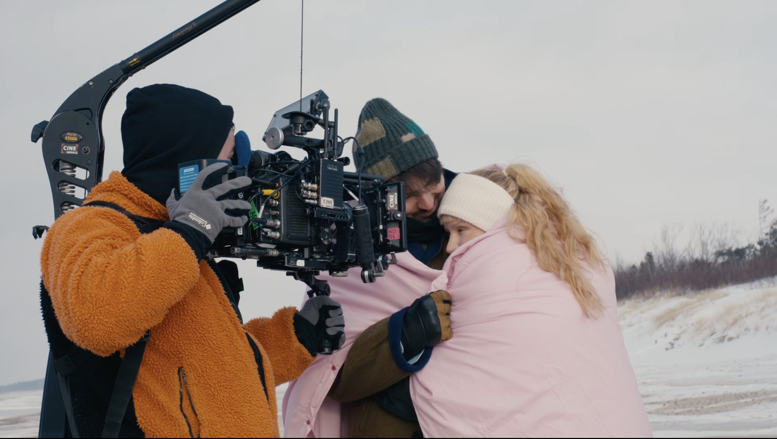 Camera crew filming Monetochka wrapped in a blanket on the Baltic shore